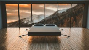 black mattress in front of a large window behind a mountain